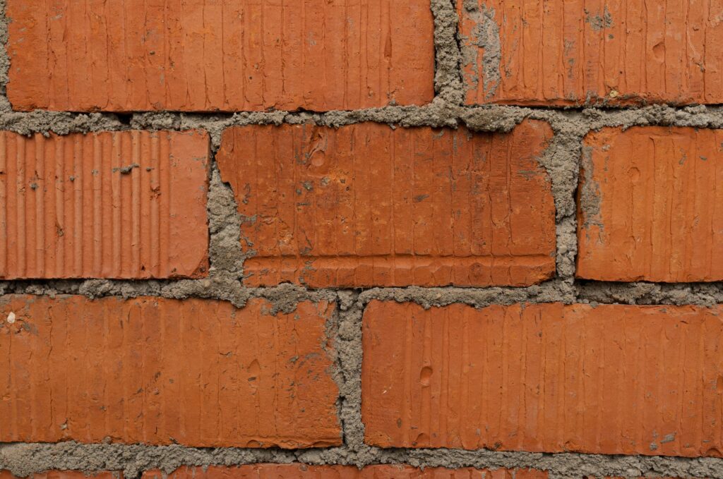A shabby red brick wall with a mortar in the gaps background
