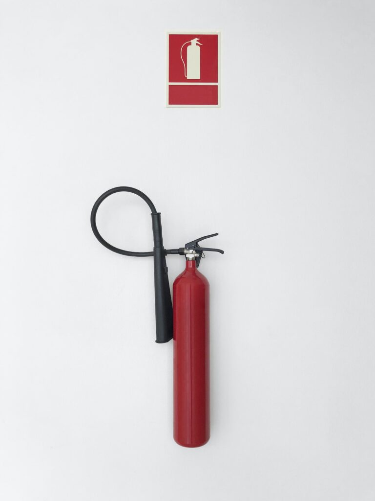 Fire extinguisher with sign alarm on a white wall. Warning